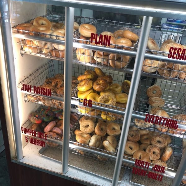 A display case at Atlantic Bagel Co. filled with various bagels, including Plain, Sesame, Egg, and Everything.