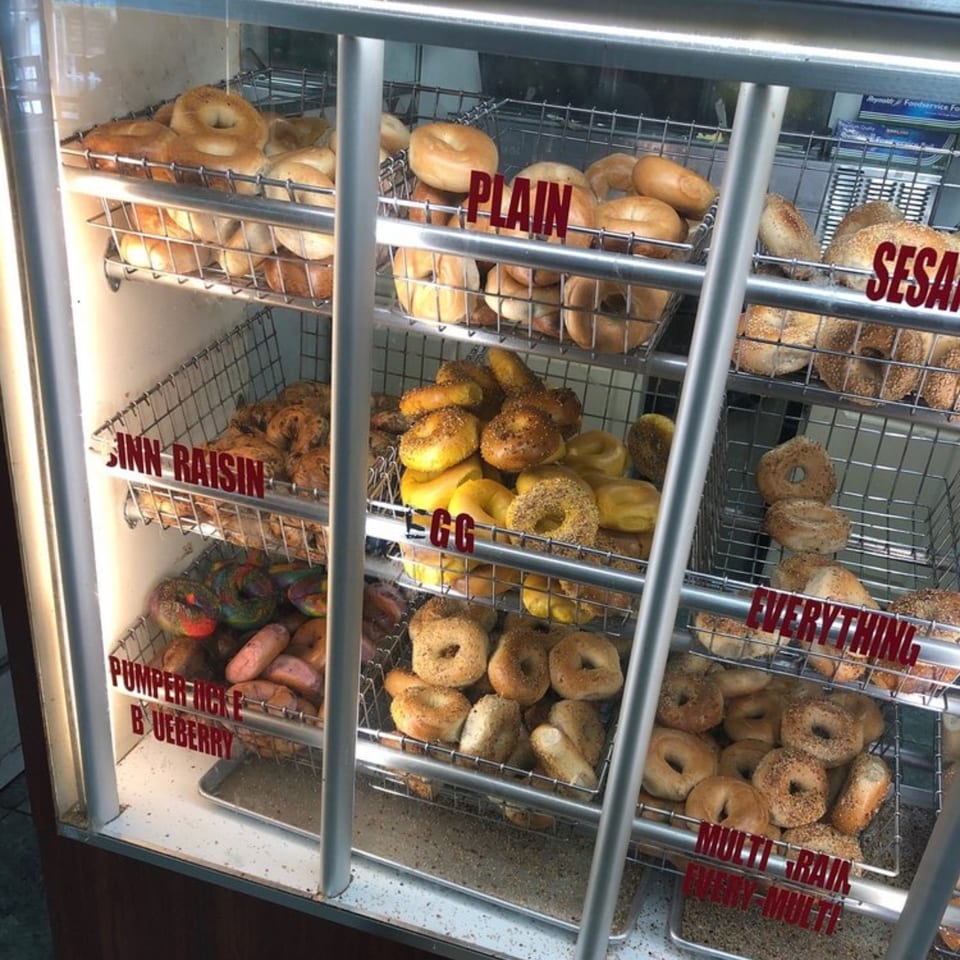 A display case at Atlantic Bagel Co. filled with various bagels, including Plain, Sesame, Egg, and Everything.