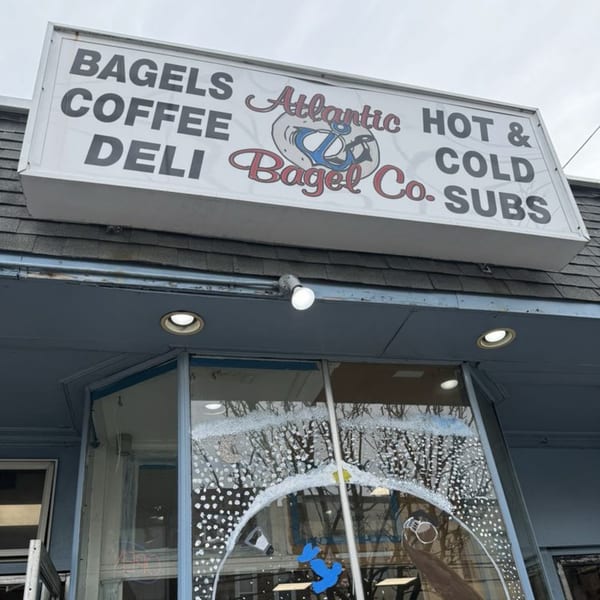 Exterior view of Atlantic Bagel Co. storefront with a sign listing bagels, coffee, deli, and subs.