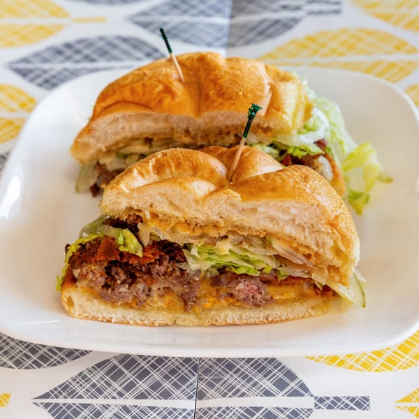 Two halves of a bagel sandwich with meat, cheese, and lettuce on a white plate.