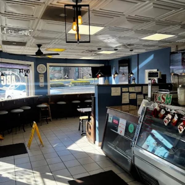 Interior of Atlantic Bagel Co. with blue walls, counter seating, and display cases.