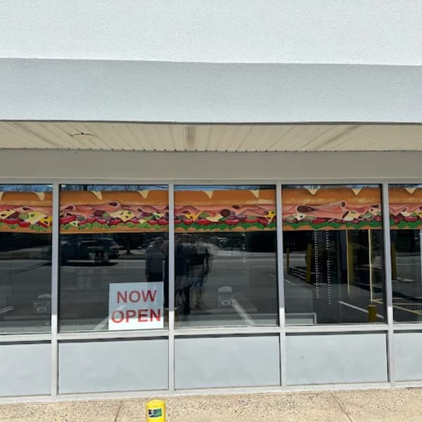 Exterior of Atlantic Bagel Co. with a "NOW OPEN" sign and a mural of a large sandwich.